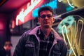 A young man fashionably dressed standing in the street at night. Illuminated signboards, neon, lights. Royalty Free Stock Photo