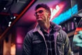 A young man fashionably dressed standing in the street at night. Illuminated signboards, neon, lights. Royalty Free Stock Photo