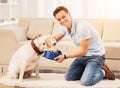 Young Man Feeding Dog Sitting on Floor in Room. Royalty Free Stock Photo