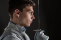 Young man fencer holding the sword in front of his