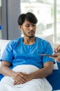 Young man with fever lying in bed with her shaking in hospital background Sick male patient lying in bed with doctor taking care Royalty Free Stock Photo