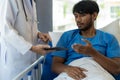 Young man with fever lying in bed with her shaking in hospital background Sick male patient lying in bed with doctor taking care Royalty Free Stock Photo