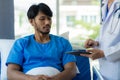 Young man with fever lying in bed with her shaking in hospital background Sick male patient lying in bed with doctor taking care Royalty Free Stock Photo