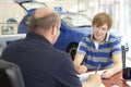 Young man filling in paperwork in car showroom Royalty Free Stock Photo