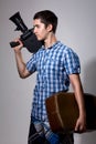 Young man filmmaker with old movie camera and a suitcase in his