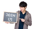 Young man finger point to chalkboard showing a phrase of join us Royalty Free Stock Photo