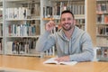 Young man with finger up happy and smiling with a book on the table in the library Royalty Free Stock Photo