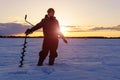 Young man fisherman on the background of dawn on a winter lake. Winter sports Royalty Free Stock Photo