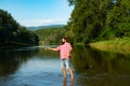Young man fishing. Fisherman with rod, spinning reel on river bank. Man catching fish, pulling rod while fishing on lake Royalty Free Stock Photo