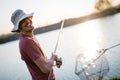 Young man fishing on a lake at sunset and enjoying hobby Royalty Free Stock Photo