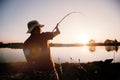 Young man fishing on lake at sunset enjoying hobby Royalty Free Stock Photo