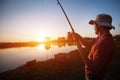 Young man fishing on lake at sunset enjoying hobby Royalty Free Stock Photo