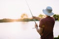 Young man fishing on lake at sunset enjoying hobby Royalty Free Stock Photo