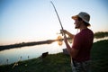 Young man fishing on a lake at sunset and enjoying hobby Royalty Free Stock Photo