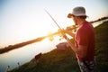 Young man fishing on a lake at sunset and enjoying hobby Royalty Free Stock Photo