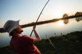 Young man fishing on a lake at sunset and enjoying hobby Royalty Free Stock Photo