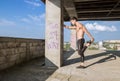 young man fit abs muscular stretching leg outdoors sunny shirtless construction building Royalty Free Stock Photo