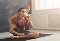 Young man in flexible yoga pose drinking tea