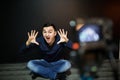 Young man in focus on digital camera screen waving hand while seated on ground against wall for concept about video Royalty Free Stock Photo