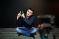 Young man in focus on digital camera screen waving hand while seated on ground against wall for concept about video Royalty Free Stock Photo