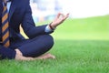 Young man in formal clothes practicing yoga on green grass outdoors Royalty Free Stock Photo