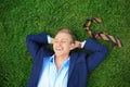 Young man in formal clothes relaxing on green grass outdoors Royalty Free Stock Photo