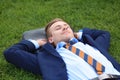 Young man in formal clothes relaxing on green grass outdoors Royalty Free Stock Photo
