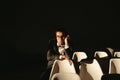 Young man in formalwear and bow tie looking away while sitting in a chair in loft interior Royalty Free Stock Photo