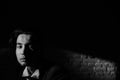 Young man in formalwear and bow tie looking away while sitting in a chair in loft interior Royalty Free Stock Photo