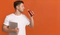 Young man freelancer holding laptop and drinking red healthy detox smoothie