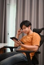 Young man freelancer sitting on comfortable chair and reading news on digital tablet. Royalty Free Stock Photo