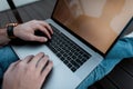 Young man freelancer works on the street. Men`s hands with a laptop. Remote work. Close-up