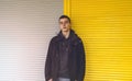 Young man in front of a yellow and gray roller shutter