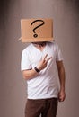 Young man gesturing with a cardboard box on his head with question mark