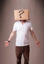 Young man gesturing with a cardboard box on his head with question mark