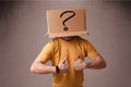 Young man gesturing with a cardboard box on his head with question mark