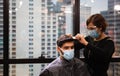 Young man getting haircut by hairdresser, Barber using scissors and comb, New normal concept Royalty Free Stock Photo