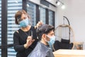 Young man getting haircut by hairdresser, Barber using scissors and comb, New normal concept Royalty Free Stock Photo