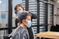 Young man getting haircut by hairdresser, Barber using scissors and comb, New normal concept Royalty Free Stock Photo