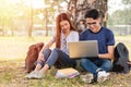 Young man and girls friend classmates sitting at park under tree Royalty Free Stock Photo