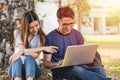 Young man and girls friend classmates sitting under tree consult Royalty Free Stock Photo