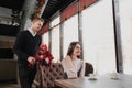 A young man gives a bouquet of red flowers to his girlfriend, wife, in a cafe by the window. Royalty Free Stock Photo