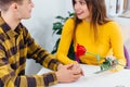 Young man gives flowers to his girlfriend, holds her hands and definitely is going to make a proposal. Royalty Free Stock Photo