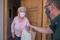 Senior woman with face mask gets neighborhood shopping assistance