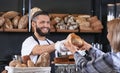 Young man giving fresh bread to woman in bakery Royalty Free Stock Photo
