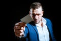 Young man giving his credit card looking at the camera, black background. Business man paying with a credit or debit Royalty Free Stock Photo