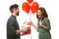 Young man giving present to his beloved girlfriend on white background. Celebration of Saint Valentine's Day