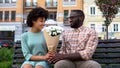 Young man giving white flower bouquet to woman sitting bench, first awkward date Royalty Free Stock Photo