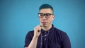 A young man in glasses with blue hair speaks on a telephone via headphones. Alternative man with headphones in ears on a Royalty Free Stock Photo