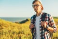 Young man, in glasses and in a cap with a backpack, hiking and enjoying the mountain landscape, adventure man hiking in the desert Royalty Free Stock Photo